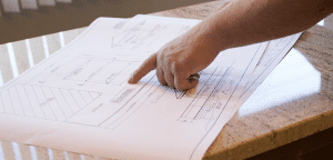 A person pointing at blueprints on a counter top.