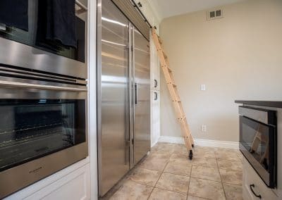 A stainless steel refrigerator with a ladder next to it.