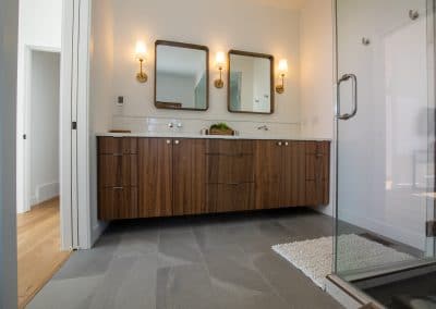 A modern bathroom with wooden cabinets and a walk in shower.
