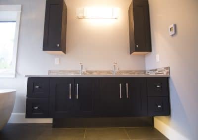A bathroom with black cabinets and a tub.