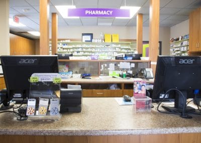A pharmacy counter with two computers and two monitors.