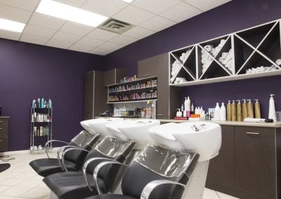 A hair salon with purple walls and chairs.