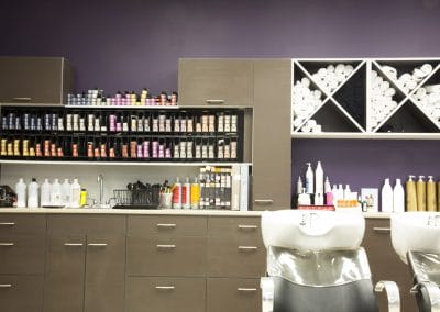 A hair salon with a purple wall and chairs.