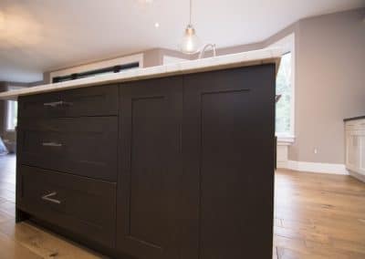 A kitchen island with black cabinets and hardwood floors.