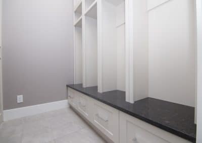 A walk in closet with white cabinets and marble counter tops.