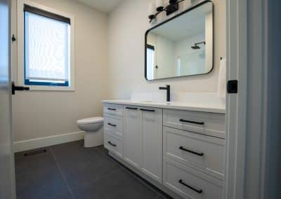A white bathroom with a black vanity and mirror.
